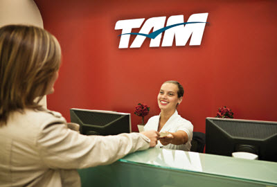 Staff member gives customer boarding pass at TAM desk